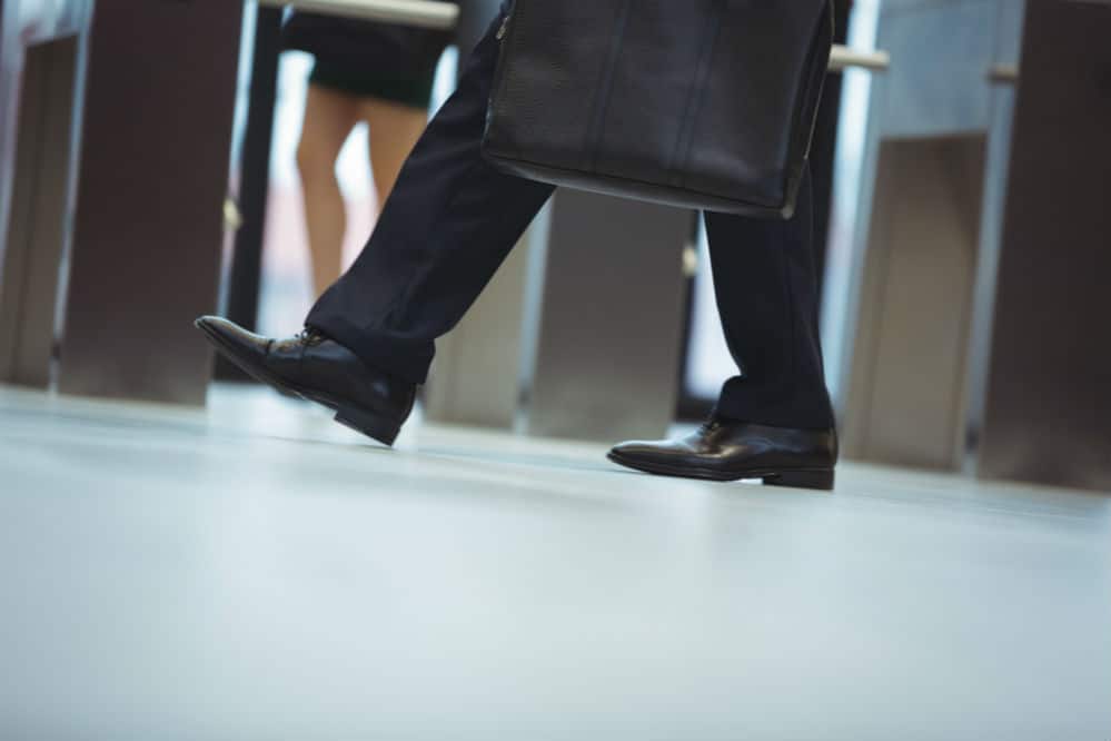Picture of a Man walking wearing leather shoes with a bag in hand and wearing office attire